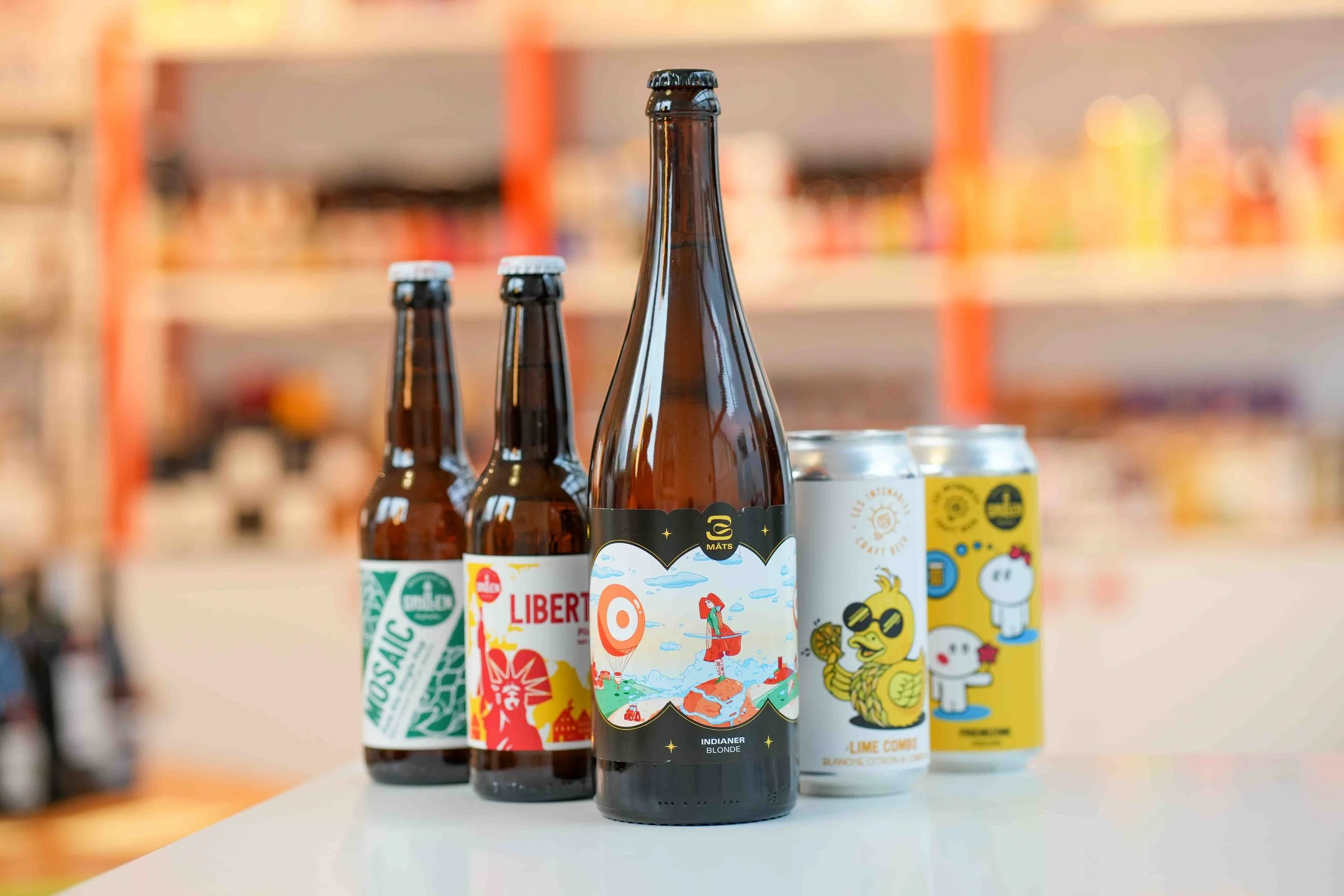 Bières alsaciennes alignées sur le comptoir de la cave : Mosaic et Liberté de la brasserie du Grillen, l'Indianer des 3 Mâts, les canettes Lime Combo et Friendzone des Intenables