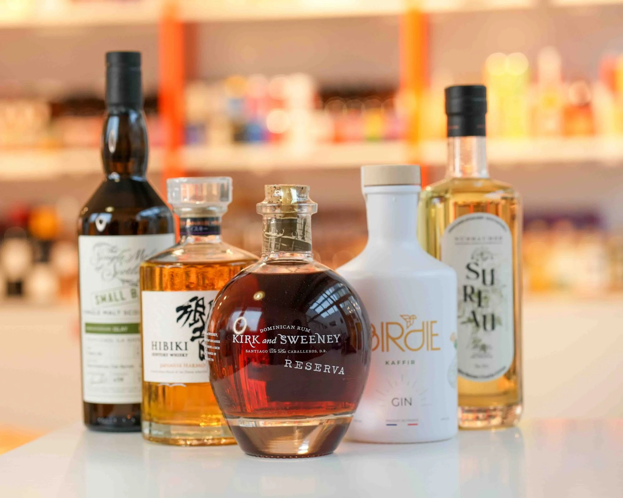 Spiritueux sur le comptoir de la cave : un single malt d'Écosse, le whisky japonais Hibiki, le rhum Kirk and Sweeney Reserva et le gin Birdie Kaffir