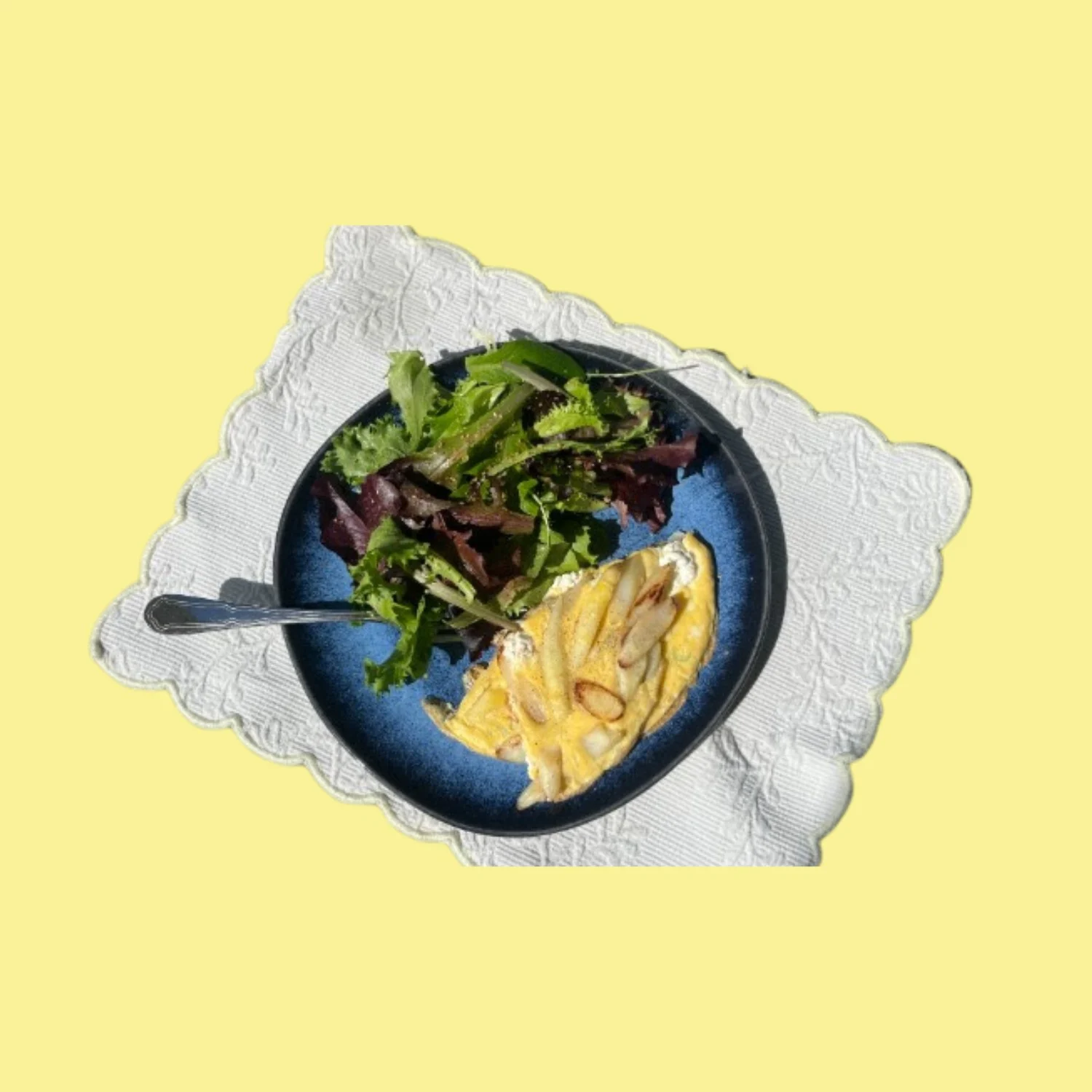 Frittata aux asperges blanches servie avec une salade verte, détourée sur fond jaune