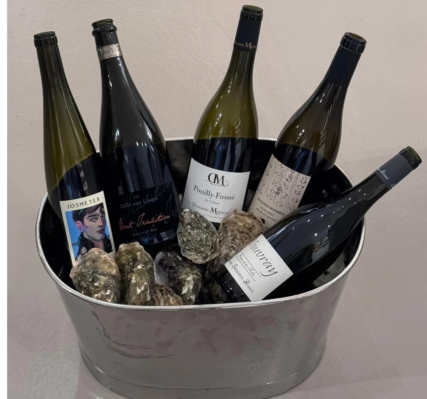 Bouteilles de vins blancs dans un seau à glace garni d'huîtres